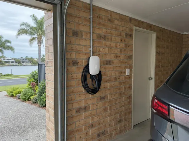 EV charger mounted on a brick garage wall beside a parked car and driveway in Paradise Point