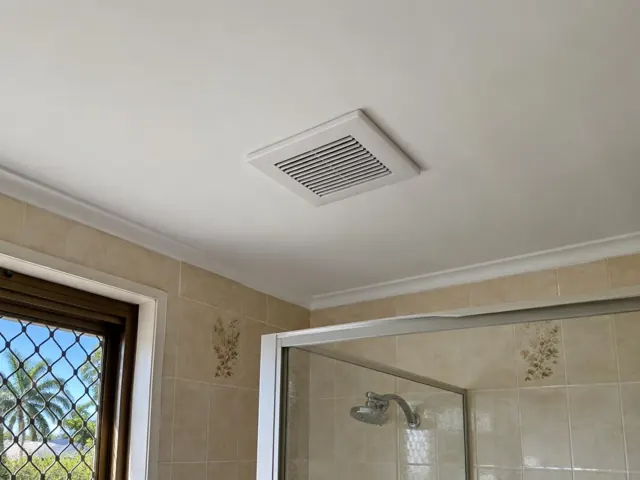 Ceiling exhaust fan above tiled bathroom shower with window and glass screen in Hope Island